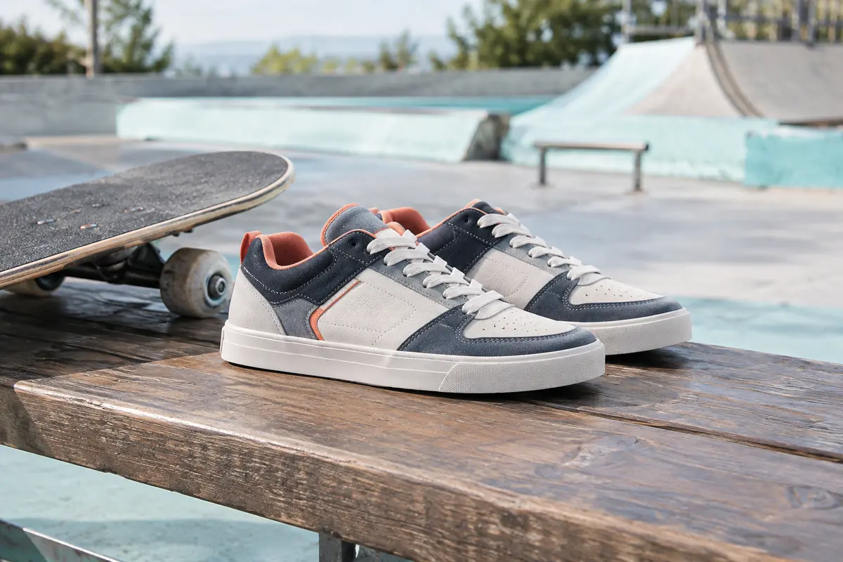 Baskets de skate pour enfant posées près d’une planche, avec semelles plates et renforts visibles.