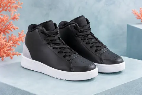 Paire de baskets montantes de basketball pour enfant, noires à talon gris et semelle blanche, posée sur un socle mat.