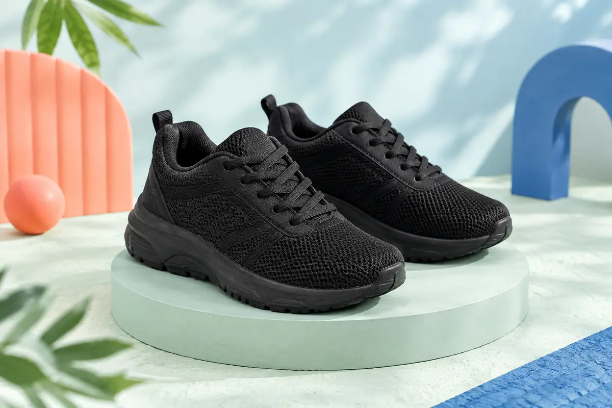 Baskets de running enfant noires en textile, à lacets, posées sur un socle clair