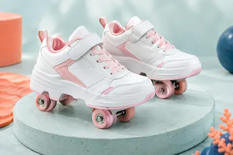 Baskets enfant Anefun blanches et roses avec quatre roulettes amovibles, posées sur un socle mat.