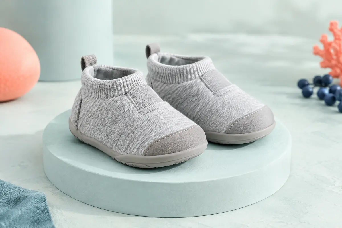 Paire de chaussons de marche bébé gris à semelle souple en caoutchouc et embout renforcé.