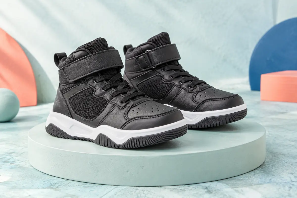 Paire de baskets montantes de basket-ball pour enfant, avec tige noire, fermeture scratch et semelle en caoutchouc.