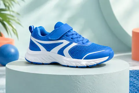 Chaussure de running enfant basse, bleu vif et blanche, présentée seule sur un socle mat.