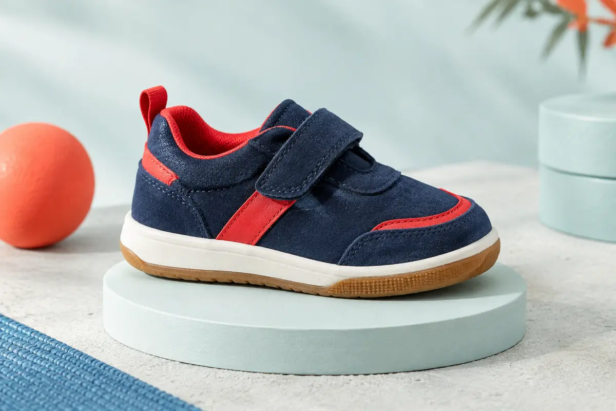 Basket basse enfant en daim bleu marine et rouge, avec fermeture auto-agrippante et semelle en caoutchouc.