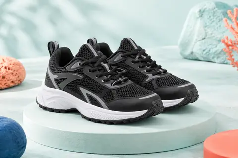 Baskets de running enfant Under Armour noires et gris anthracite, avec tige en maille et semelle à reliefs.